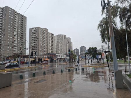 Calle de Santiago mojada por la lluvia, con edificios y un semáforo, durante el temporal de julio de 2026